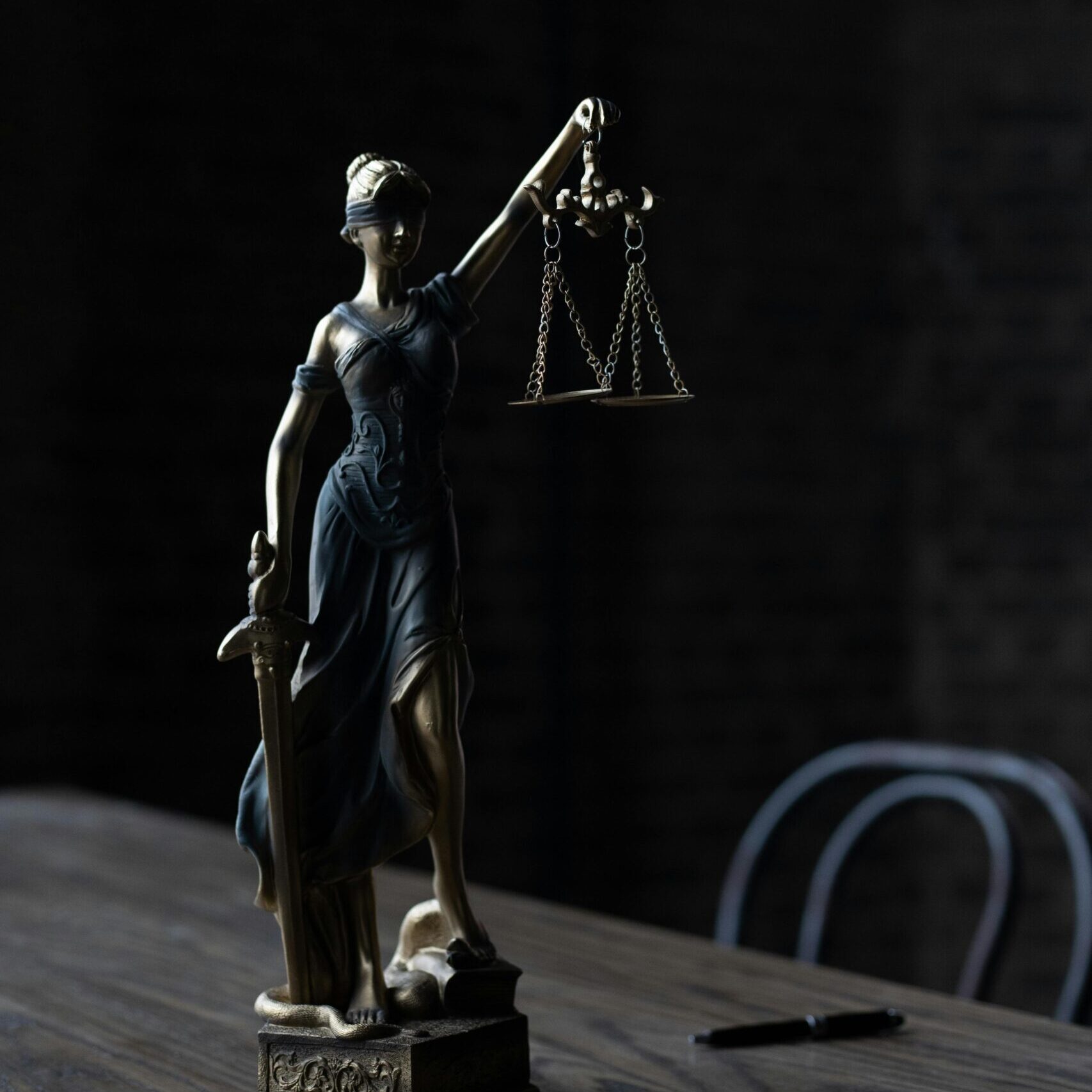 Dramatic lighting on Lady Justice figurine, symbolizing law and fairness.